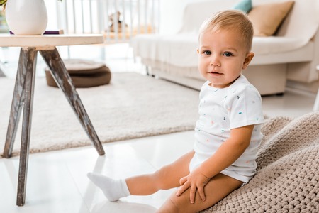 adorable toddler sitting and looking at camera in nursery roomの写真素材