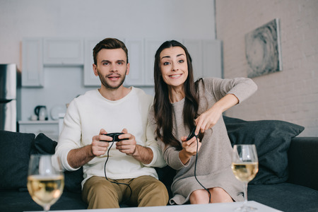 happy young couple playing retro video game on couch at homeの写真素材