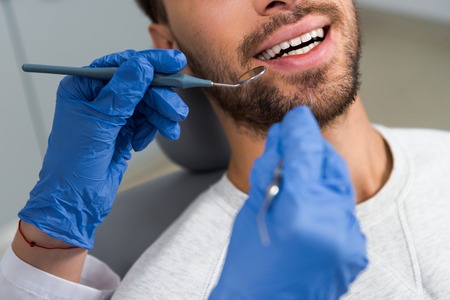 cropped shot of female dentist examining teeth of happy clientの写真素材