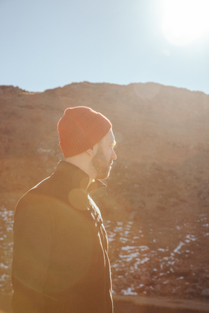 handsome young man in red hat looking away in front of mountain on sunny day, Carpathians, Ukraineの写真素材