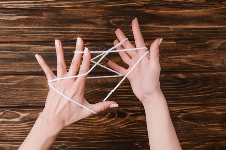 Partial view of woman holding white yarn for knitting on hands on wooden tabletopの写真素材