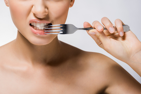 Young beautiful woman holding silver fork near teethの写真素材