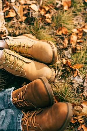Top view on two pairs of orange boots in beautiful foliage in autumnの写真素材