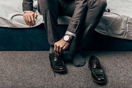 cropped image of businessman putting on shoes in bedroom at homeの写真素材