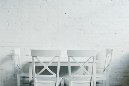 Interior of dinner room with wooden table and chairs in front of brick wall