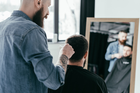 rear view of barber combing customer hair at barbershopの写真素材