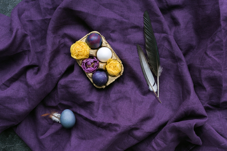 Easter eggs and flowers in carton on textile backgroundの写真素材