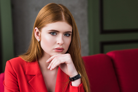 Attractive stylish young woman with wristwatch posing in red jacketの写真素材