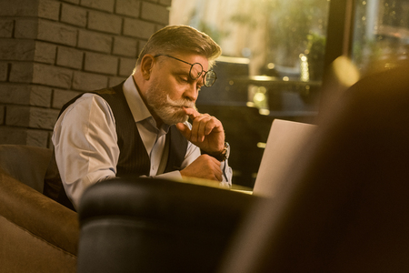 side view of pensive senior businessman looking at laptop screen in cafeの写真素材