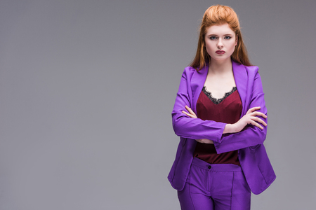 Young stylish female model dressed in purple suit isolated on greyの写真素材