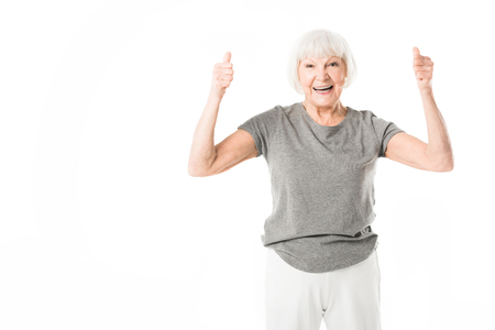 Smiling senior sportswoman showing thumbs up gesture isolated on whiteの写真素材