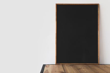 one big empty blackboard on wooden table on whiteの写真素材