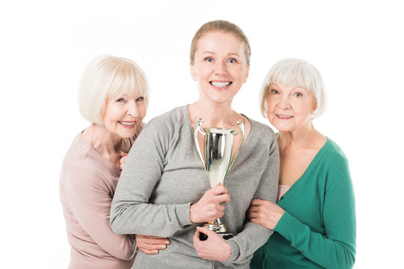 Smiling stylish women celebrating with trophy isolated on white