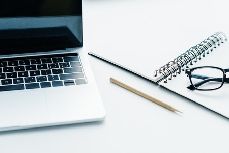 Pencil, textbook with eyeglasses and laptop on white surfaceの写真素材
