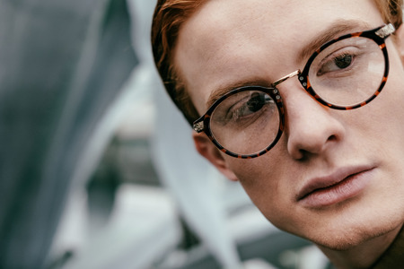 headshot of stylish man with red hair in eyeglasses looking awayの写真素材