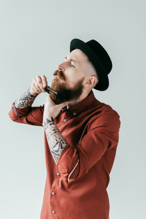 side view of bearded handsome man combing beard isolated on whiteの写真素材