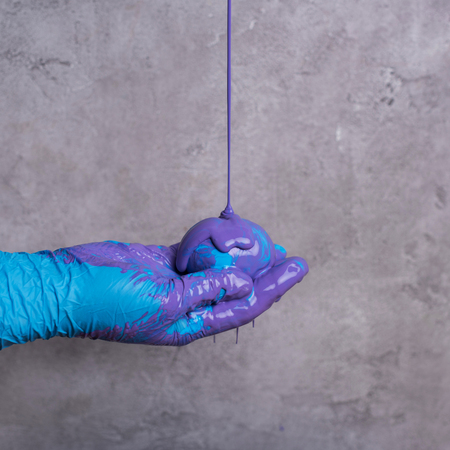 Paint pouring on egg in hand on grey backgroundの写真素材