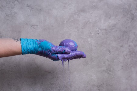 Woman holding egg in paint on grey backgroundの写真素材