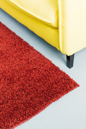 Partial view of furry rug and yellow leather couchの写真素材