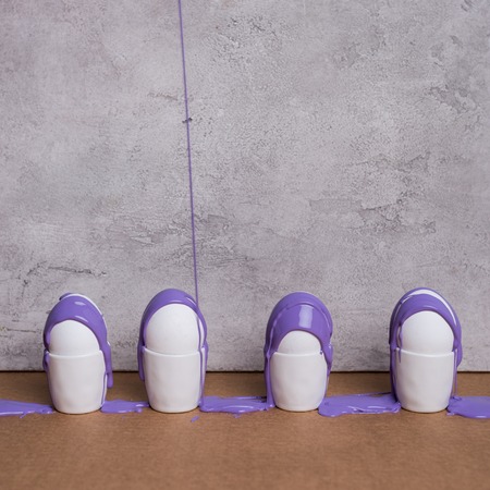 Paint streaming on eggs in cups on grey backgroundの写真素材