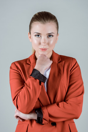 Stylish woman with hand on chin isolated on greyの写真素材