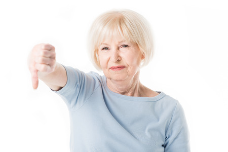 Senior woman with thumb down gesture isolated on whiteの写真素材
