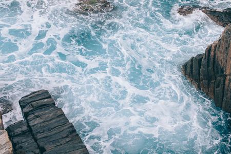 beautiful wavy sea with rocks at coastline in Riomaggiore, Italy