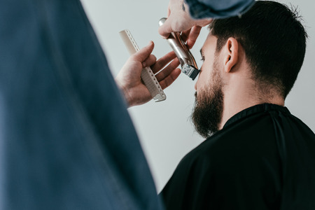 cropped image of barber trimming customer beard at barbershopの写真素材