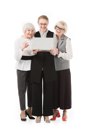 Stylish businesswomen in eyeglasses looking at laptop isolated on whiteの写真素材