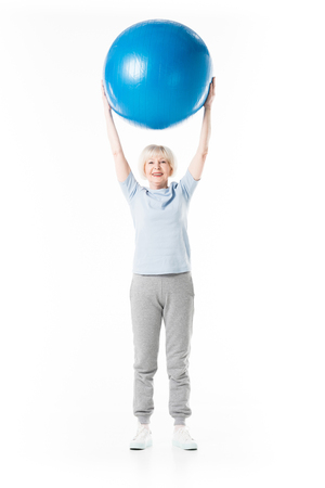 Senior sportswoman with arms up holding fitness ball isolated on whiteの写真素材
