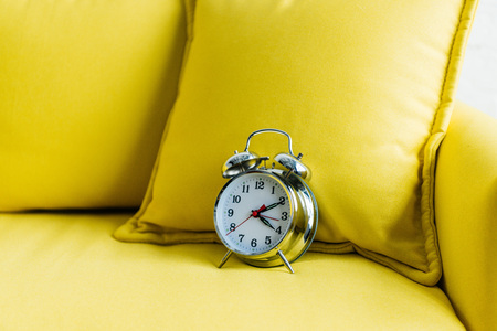 Close up view of metalic alarm clock on yellow couchの写真素材