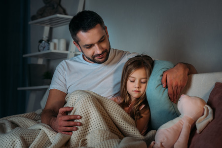 portrait of father looking at innocent sleeping daughterの写真素材