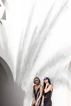 attractive fashionable girls in sunglasses posing near white building at resort in Egyptの写真素材