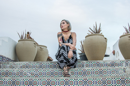 beautiful woman in dress sitting on stairs and looking away at resort in Egyptの写真素材