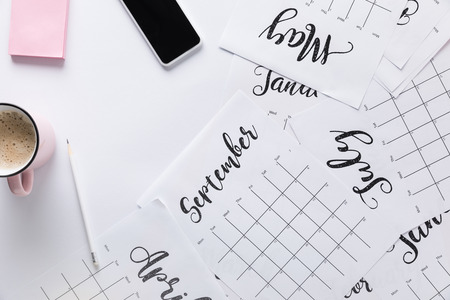 flat lay with calendar, smartphone, cup of coffee and sticky notes isolated on whiteの写真素材