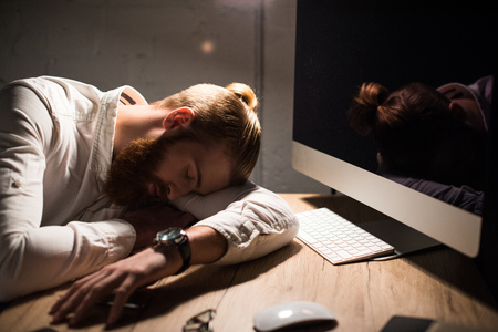 businessman sleeping on table at workplace in eveningの写真素材