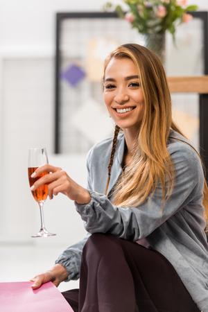 asian girl celebrating with glass of champagne in modern officeの写真素材