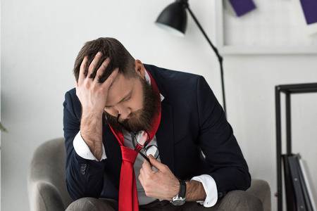 overworked businessman in stylish suit sitting in armchairの写真素材
