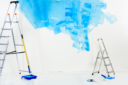 ladders and paint roller brushes in blue paintの写真素材