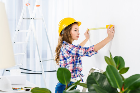 young woman measuring wall with tape measureの写真素材