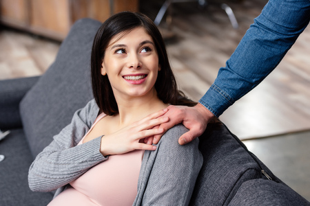 cropped shot of smiling young pregnant woman looking at husband at homeの写真素材