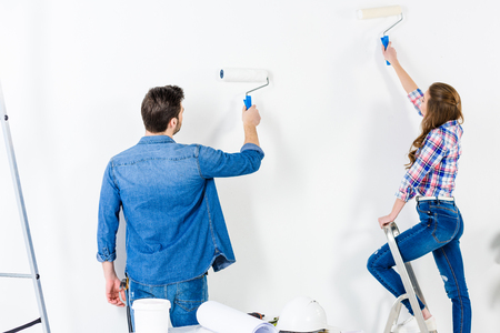 rear view of couple painting wall with white paintの写真素材
