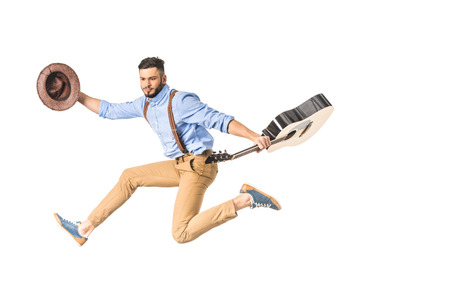 young handsome musician with hat and guitar jumping isolated on whiteの写真素材
