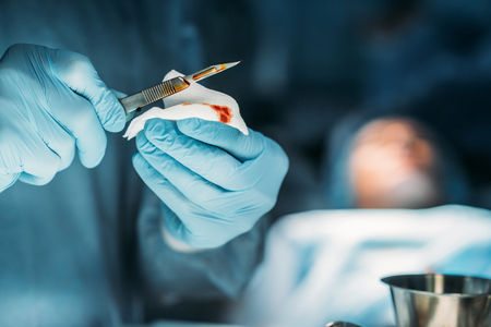 cropped image of surgeon cleaning scalpel from bloodの写真素材
