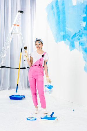smiling girl holding paint brush and bucket with paintの写真素材