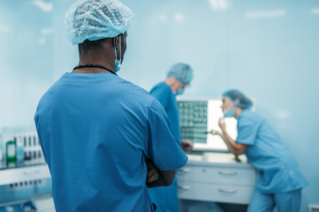 rear view of multicultural doctors looking at patient x-rayの写真素材
