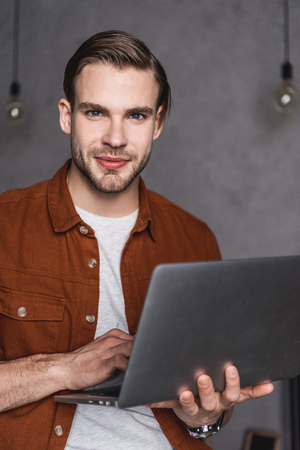 close-up portrait of handsome man with laptop looking at cameraの写真素材