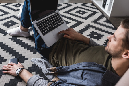 young relaxed man working with laptop while sitting on floorの写真素材