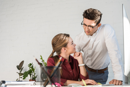 young handsome businessman flirtling with female colleague at officeの写真素材