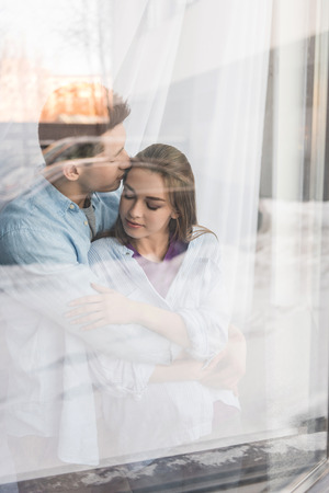 view through window on boyfriend kissing girlfriendの写真素材